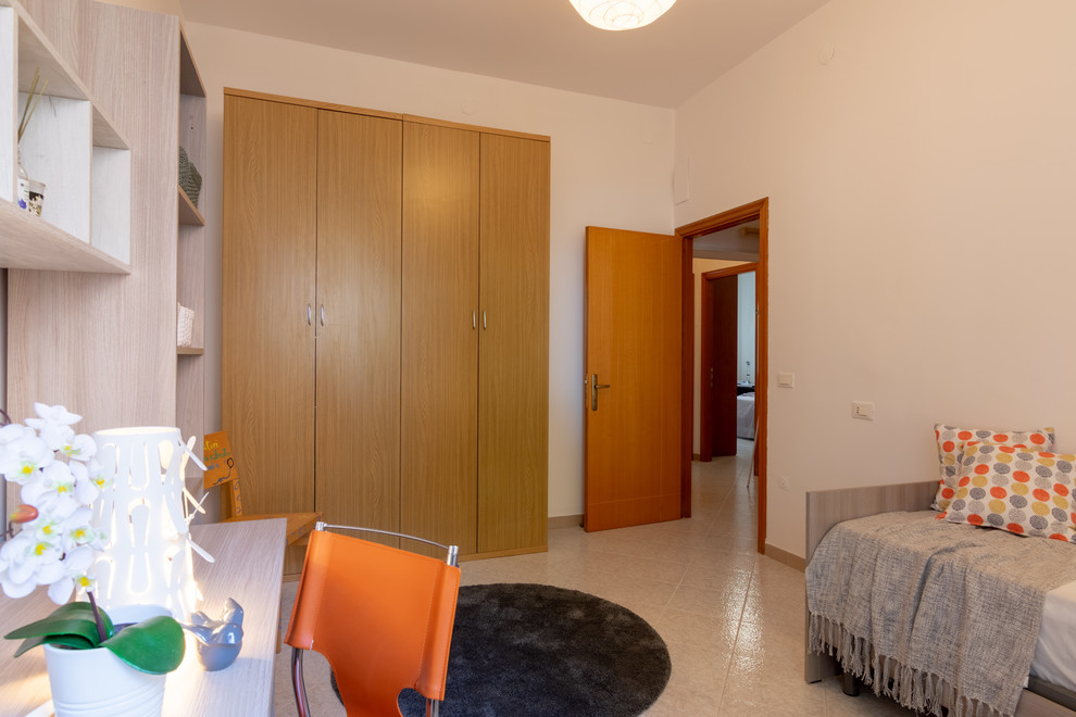 Modelo de habitación de invitados moderna de tamaño medio con paredes beige, suelo de baldosas de porcelana y suelo multicolor