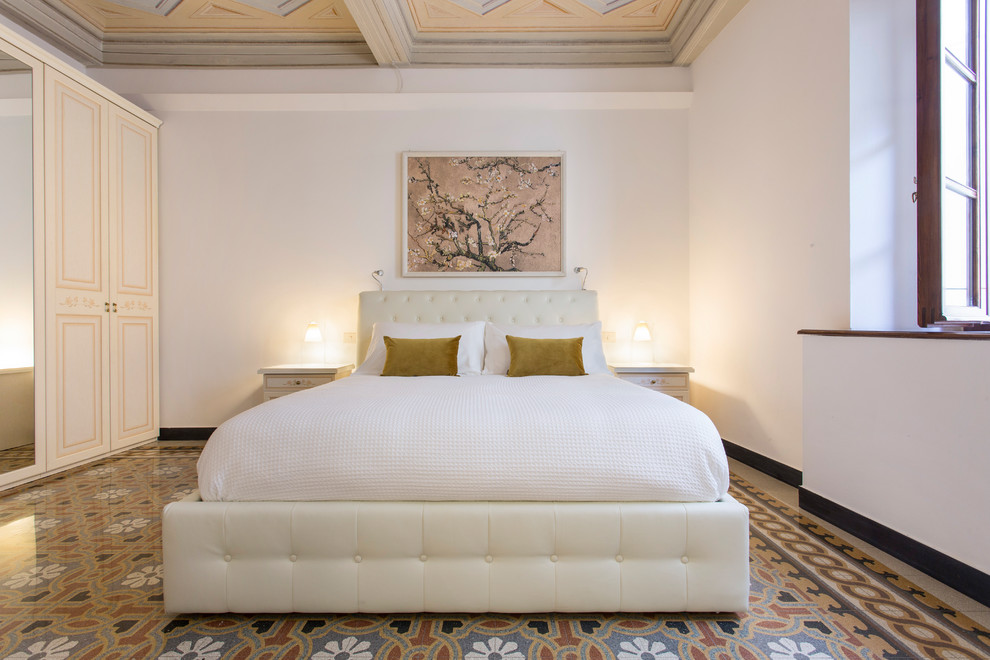 Foto de dormitorio principal mediterráneo de tamaño medio sin chimenea con paredes blancas, suelo de baldosas de cerámica y suelo multicolor