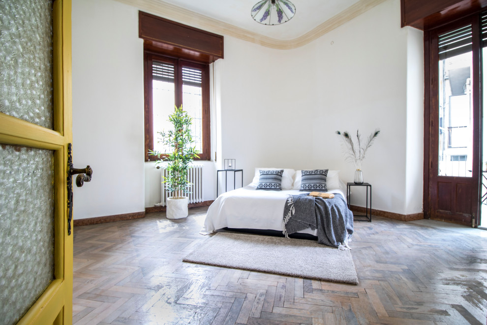 Photo of a contemporary bedroom in Catania-Palermo with white walls, medium hardwood flooring and brown floors.