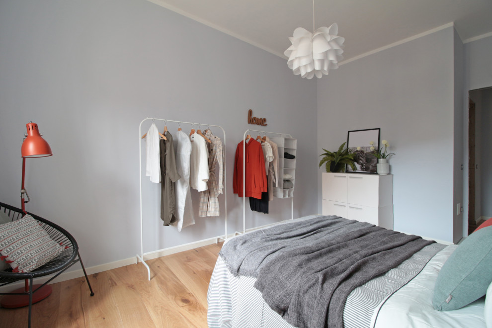 Modelo de dormitorio principal escandinavo de tamaño medio con paredes grises y suelo de madera clara