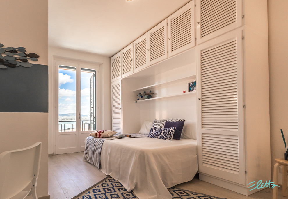 Foto de dormitorio tipo loft marinero pequeño con paredes blancas y suelo de madera clara