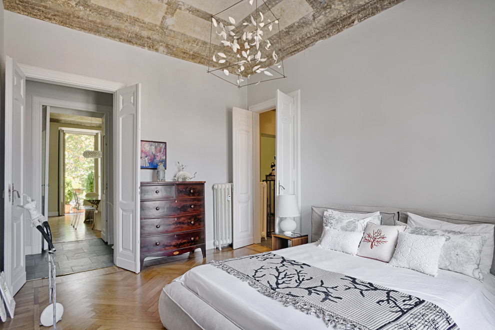 This is an example of a large mediterranean master bedroom in Amsterdam with white walls and light hardwood flooring.