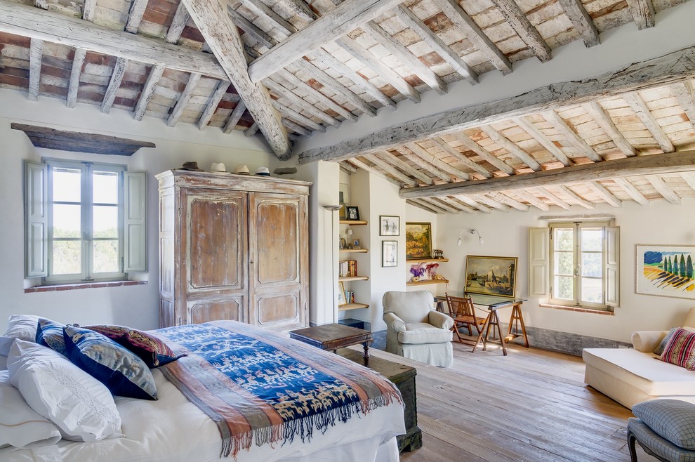 Ejemplo de dormitorio principal de estilo de casa de campo extra grande con suelo de madera clara, paredes blancas y techo inclinado