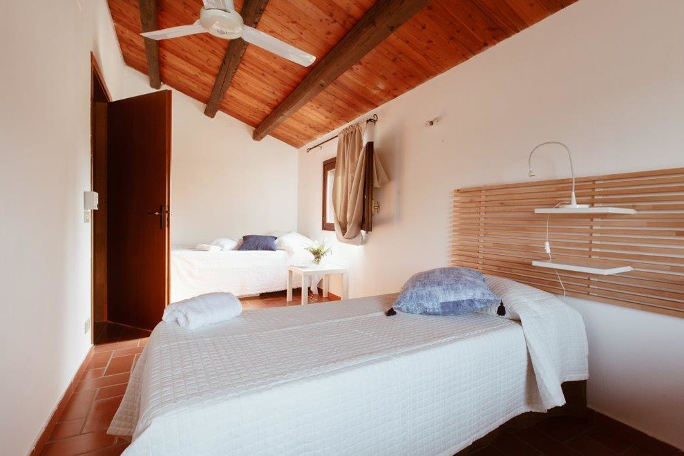 Foto de habitación de invitados mediterránea de tamaño medio con paredes blancas, suelo de madera clara y suelo marrón