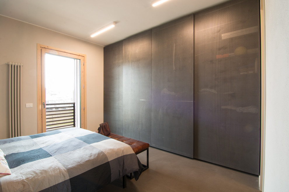 Ejemplo de dormitorio principal industrial de tamaño medio con paredes grises, suelo de cemento y suelo gris