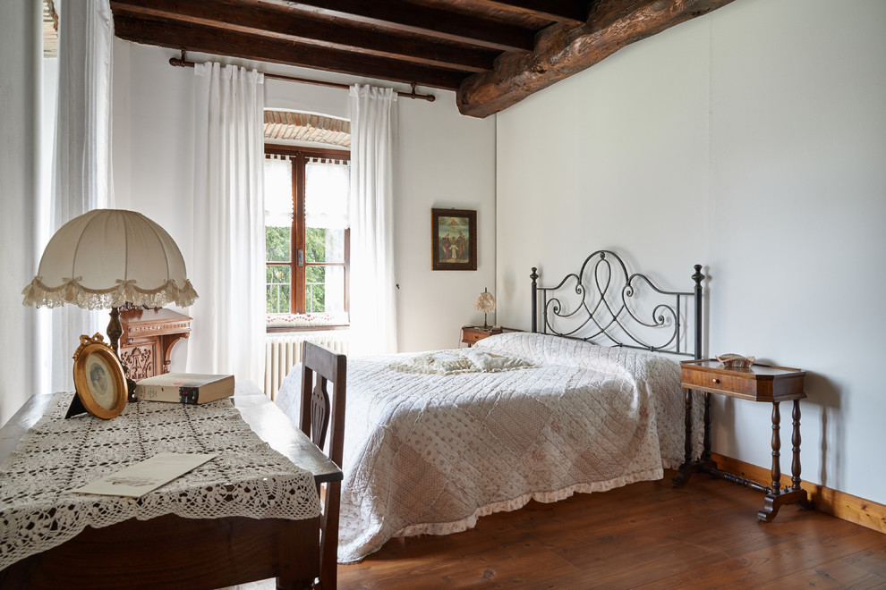 Diseño de dormitorio principal de estilo de casa de campo con paredes blancas y suelo de madera en tonos medios
