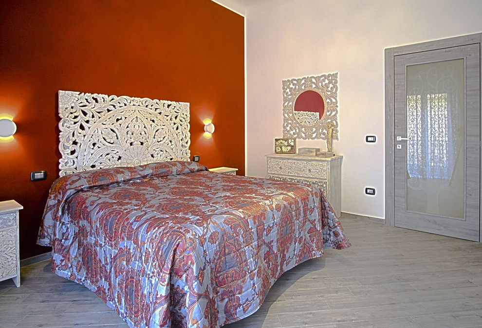 Esempio di una camera matrimoniale etnica con pareti rosse, pavimento in gres porcellanato e pavimento grigio
