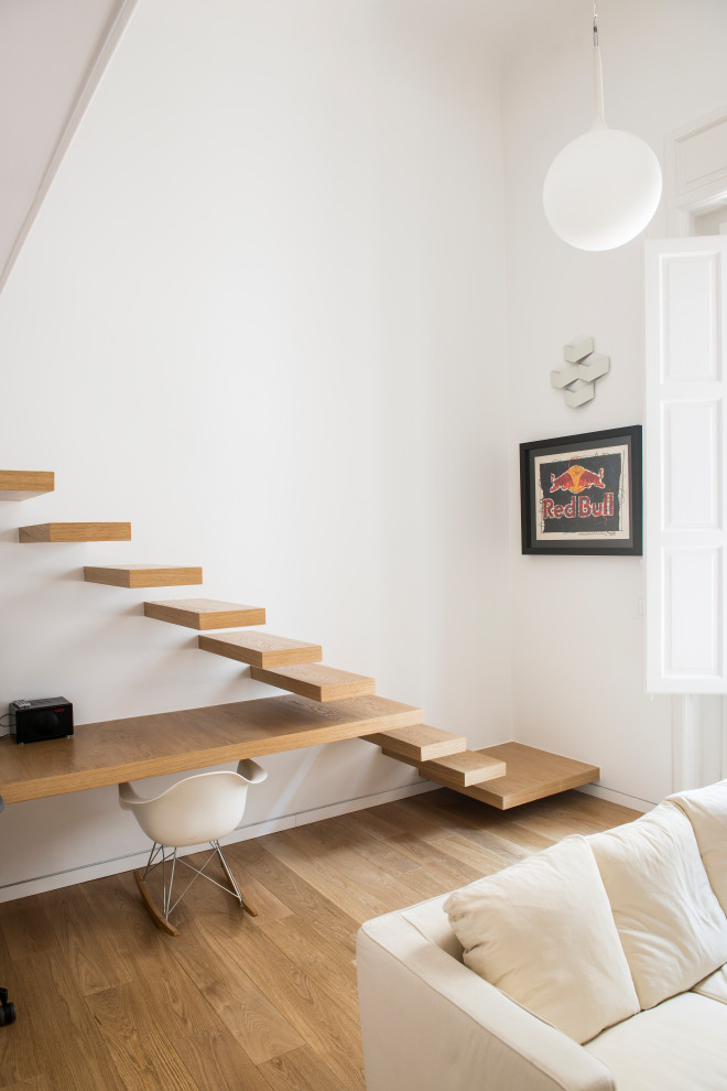 Imagen de dormitorio tipo loft contemporáneo de tamaño medio con paredes blancas y suelo de madera clara