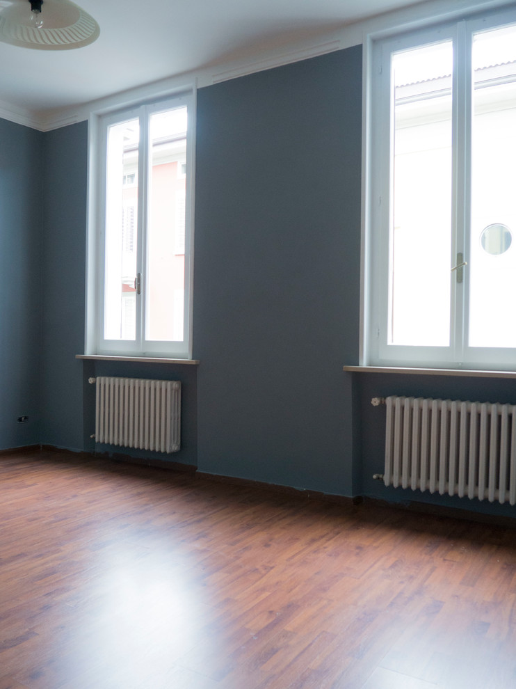 Foto de dormitorio principal retro grande con paredes azules, suelo laminado y suelo marrón