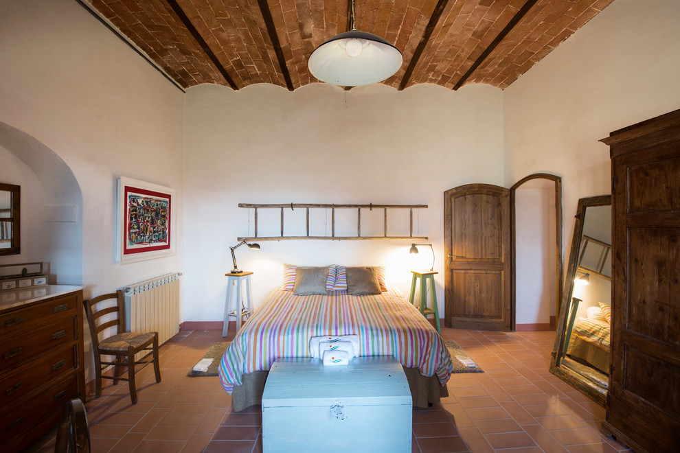 Idée de décoration pour une chambre parentale champêtre de taille moyenne avec un mur blanc, un sol en brique et un sol marron.