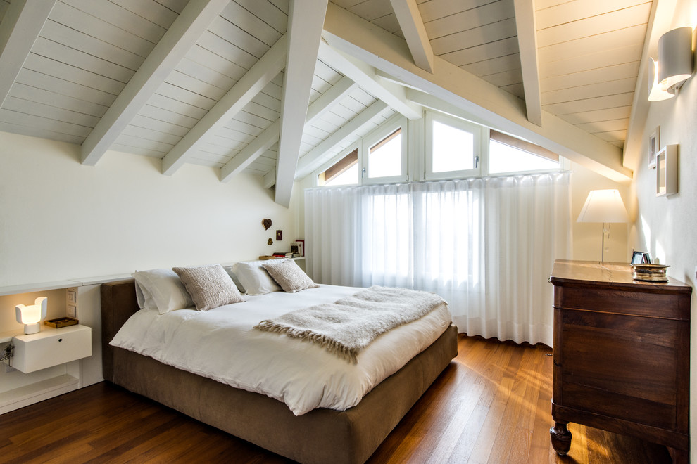 Ispirazione per un'ampia camera matrimoniale minimalista con pareti bianche, pavimento in legno massello medio e pavimento marrone