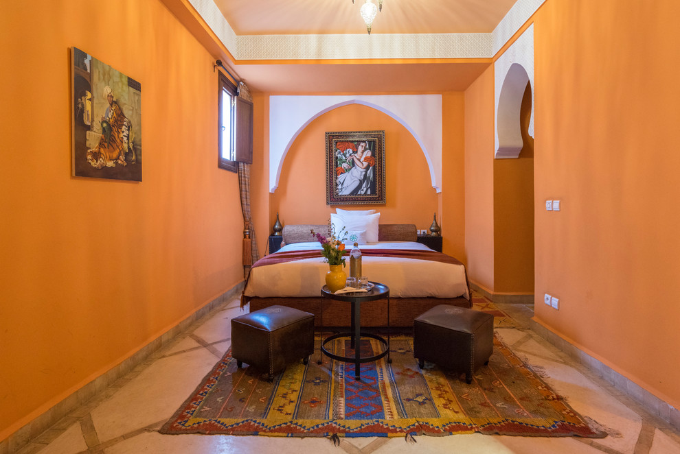 На фото: гостевая спальня (комната для гостей) в средиземноморском стиле с оранжевыми стенами и бежевым полом с