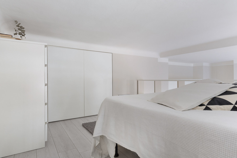 Small scandinavian mezzanine bedroom in Milan with grey walls, laminate floors and beige floors.