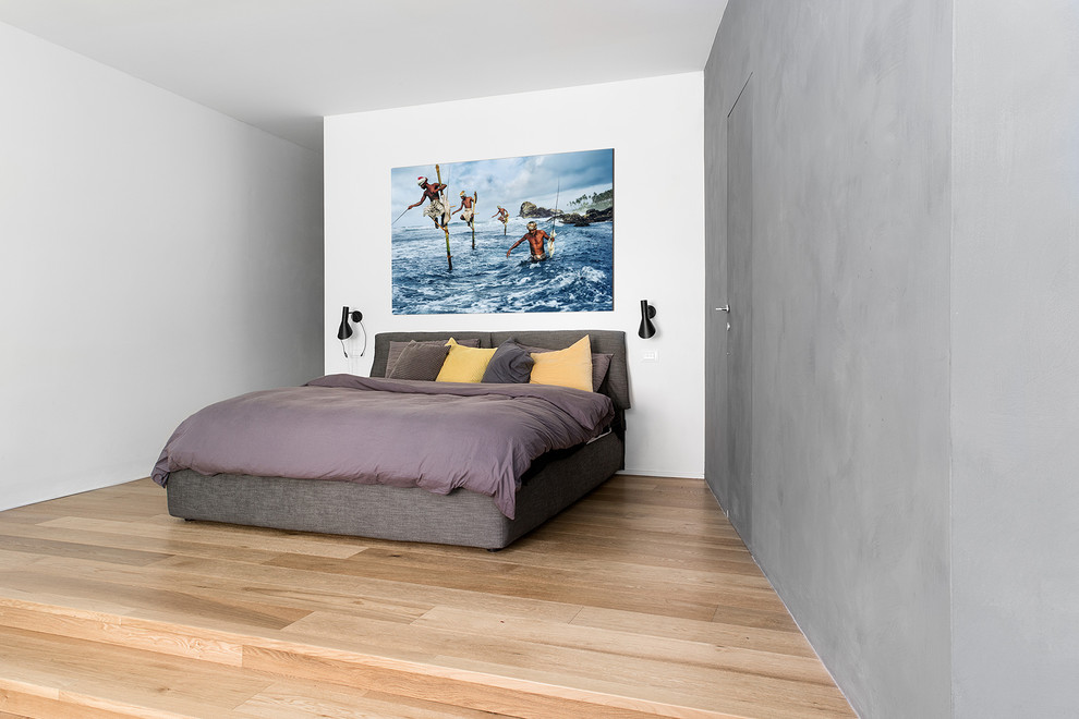 Diseño de dormitorio tipo loft industrial de tamaño medio con paredes grises y suelo de madera clara