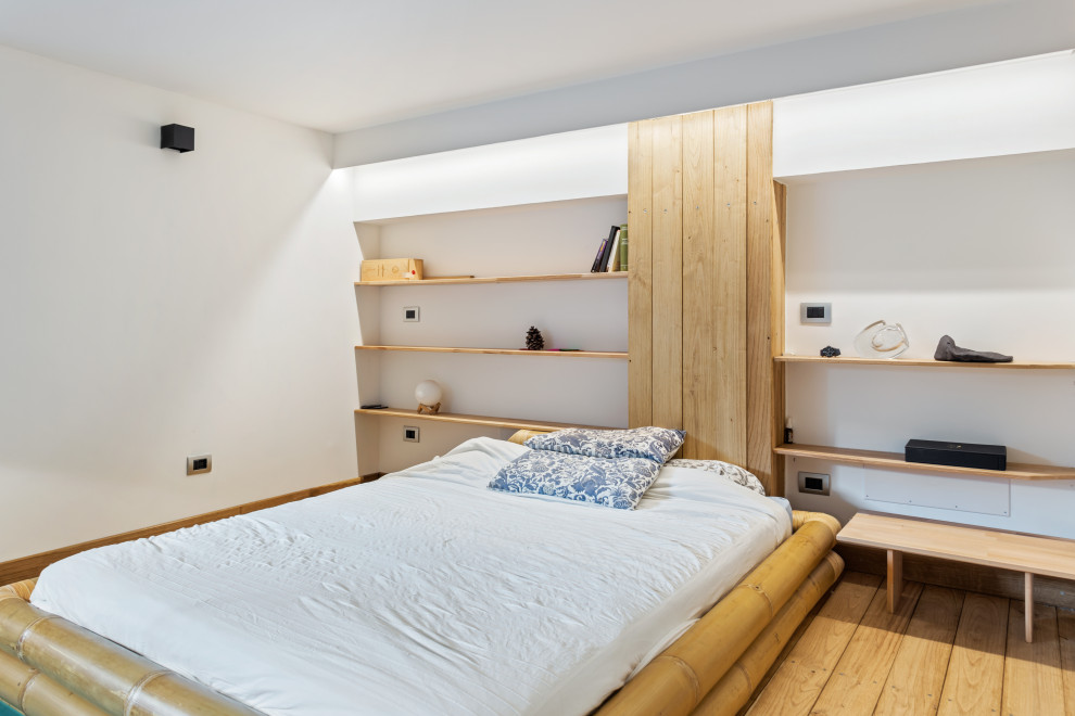 This is an example of a medium sized contemporary mezzanine bedroom in Rome with white walls, medium hardwood flooring and beige floors.
