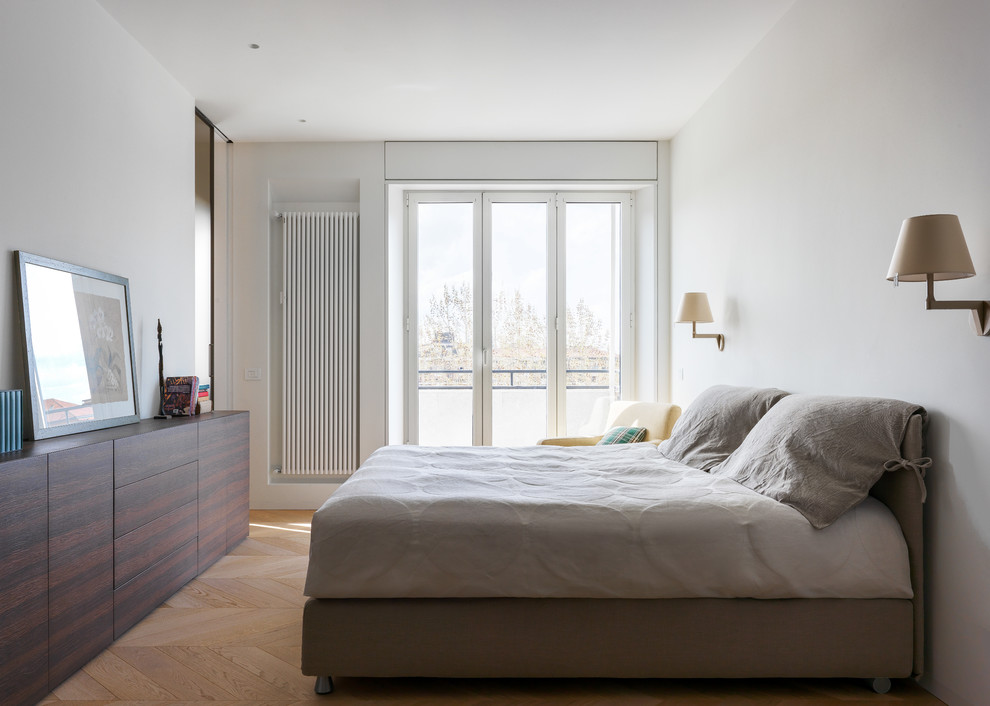 This is an example of a modern master bedroom in Milan with white walls, light hardwood flooring and beige floors.