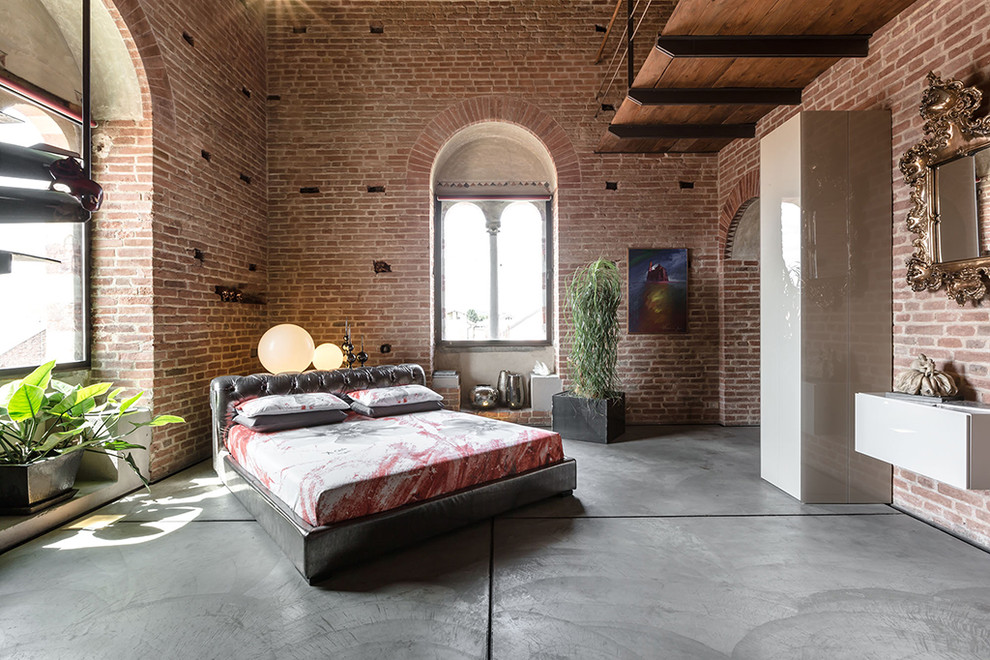 Geräumiges Industrial Hauptschlafzimmer mit roter Wandfarbe, Betonboden und grauem Boden in Turin