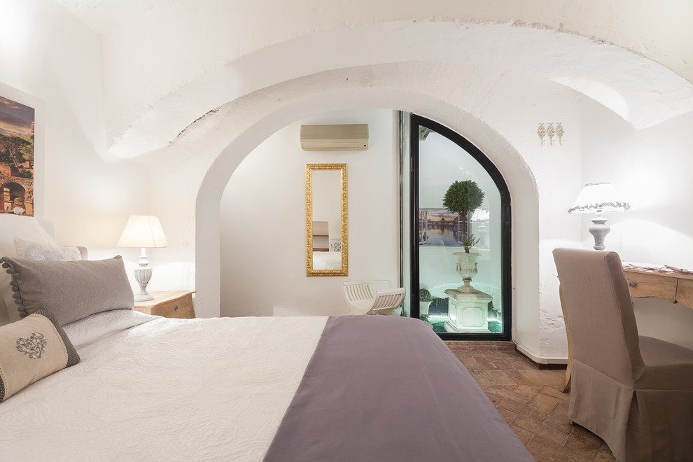 Пример оригинального дизайна: большая хозяйская спальня в стиле кантри с белыми стенами и кирпичным полом