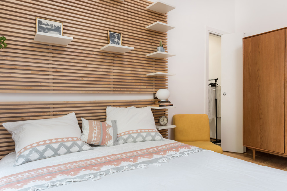 Diseño de dormitorio principal moderno de tamaño medio con paredes blancas y suelo de madera en tonos medios