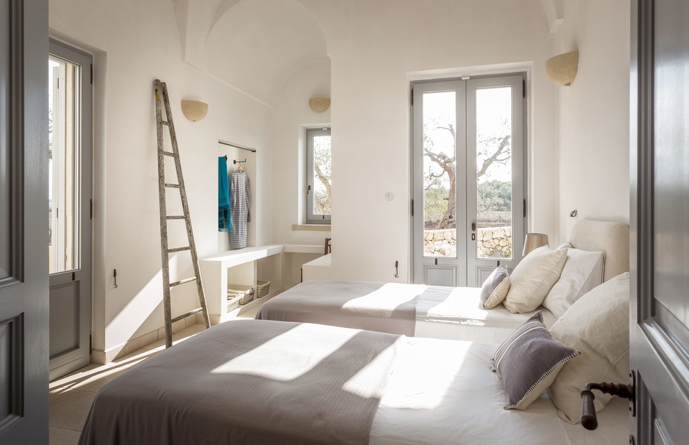 Immagine di una camera degli ospiti mediterranea con pareti bianche e pavimento beige