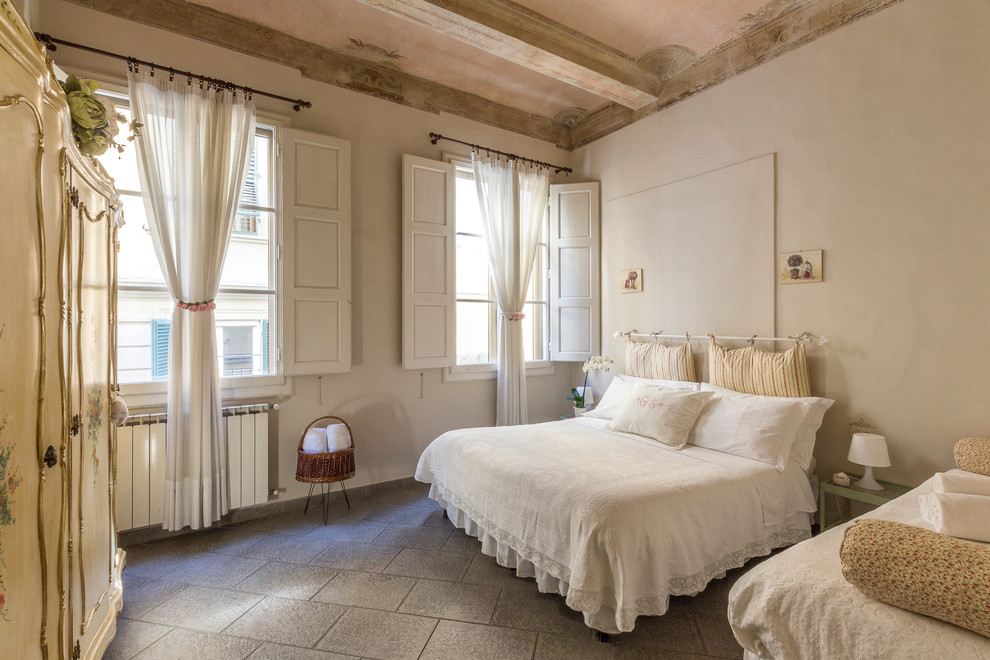 Immagine di una camera da letto mediterranea con pareti bianche e pavimento grigio