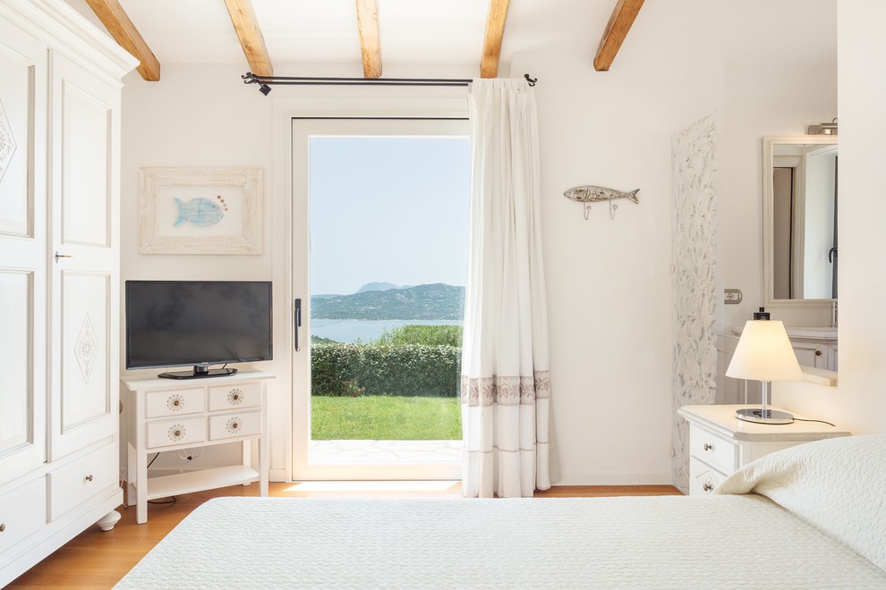 Mediterranes Gästezimmer mit weißer Wandfarbe, braunem Holzboden und braunem Boden in Sonstige