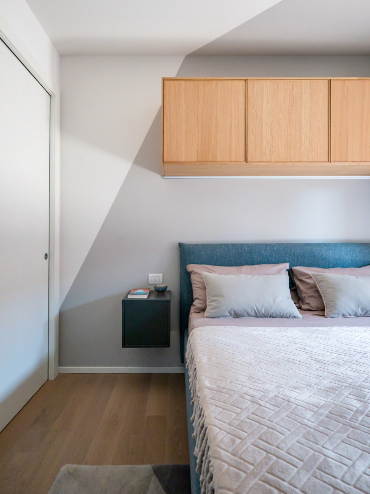 ミラノにある小さな北欧スタイルのおしゃれな主寝室 (マルチカラーの壁、淡色無垢フローリング)