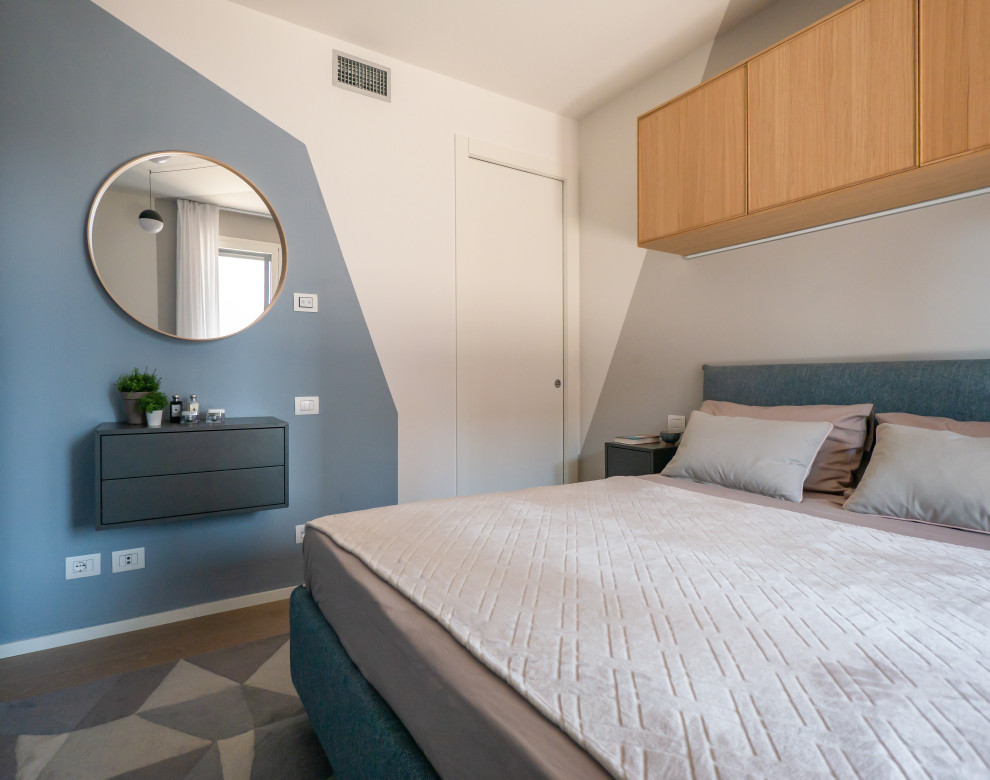 Kleines Skandinavisches Hauptschlafzimmer mit bunten Wänden und hellem Holzboden in Mailand