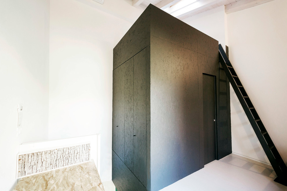 Kleines Modernes Schlafzimmer im Loft-Style mit weißer Wandfarbe und grauem Boden in Bologna