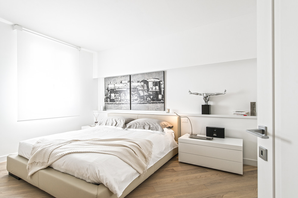 Design ideas for a large contemporary master bedroom in Milan with white walls and light hardwood flooring.