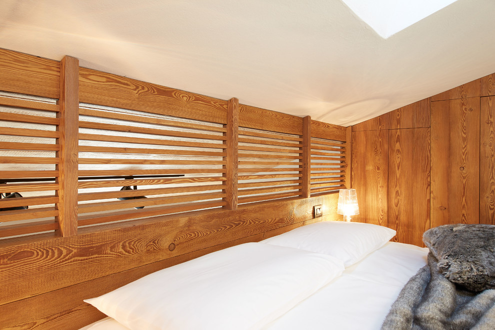 Kleines Rustikales Hauptschlafzimmer ohne Kamin mit weißer Wandfarbe und braunem Holzboden in Turin