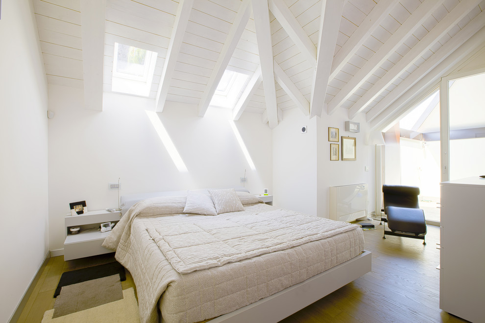 Foto de dormitorio moderno grande con paredes blancas, suelo de madera clara y vigas vistas