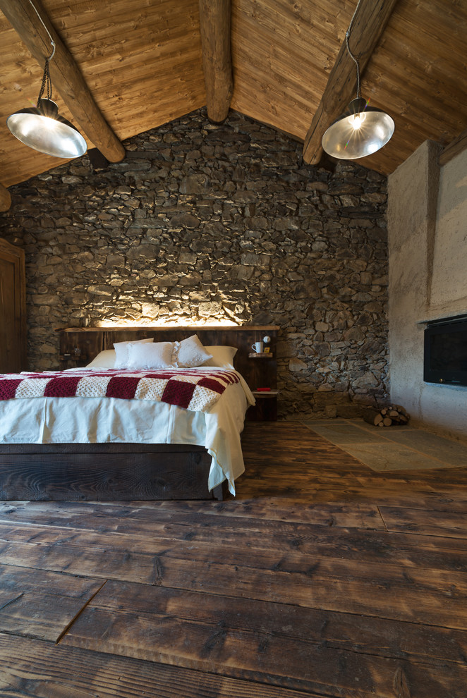 Ejemplo de dormitorio principal rústico grande con paredes multicolor, suelo de madera oscura, chimenea lineal, marco de chimenea de yeso y suelo marrón