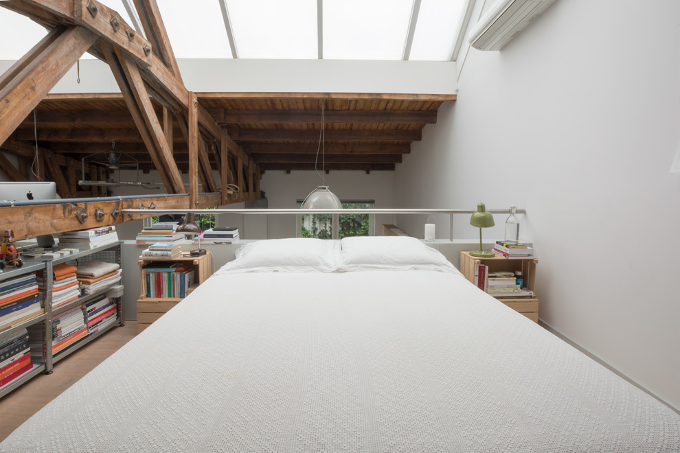 Modelo de dormitorio tipo loft con paredes blancas y suelo de madera clara
