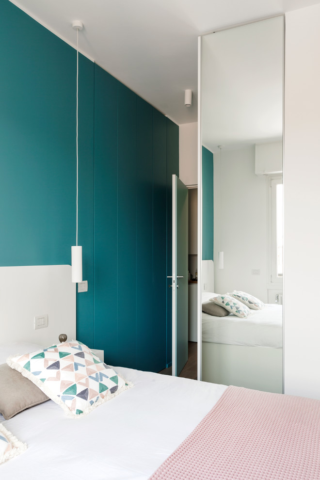 Immagine di una piccola camera matrimoniale contemporanea con pareti blu e pavimento in legno massello medio
