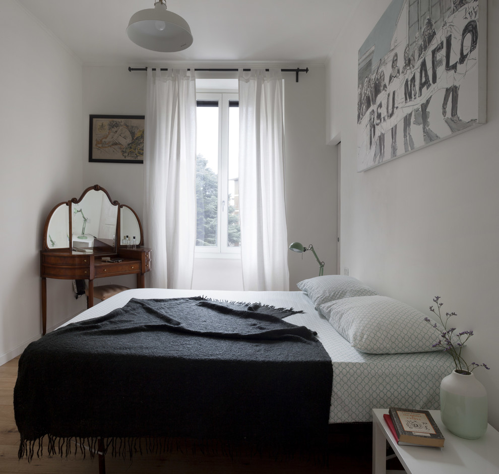 Mittelgroßes Skandinavisches Hauptschlafzimmer mit weißer Wandfarbe, hellem Holzboden und braunem Boden in Mailand