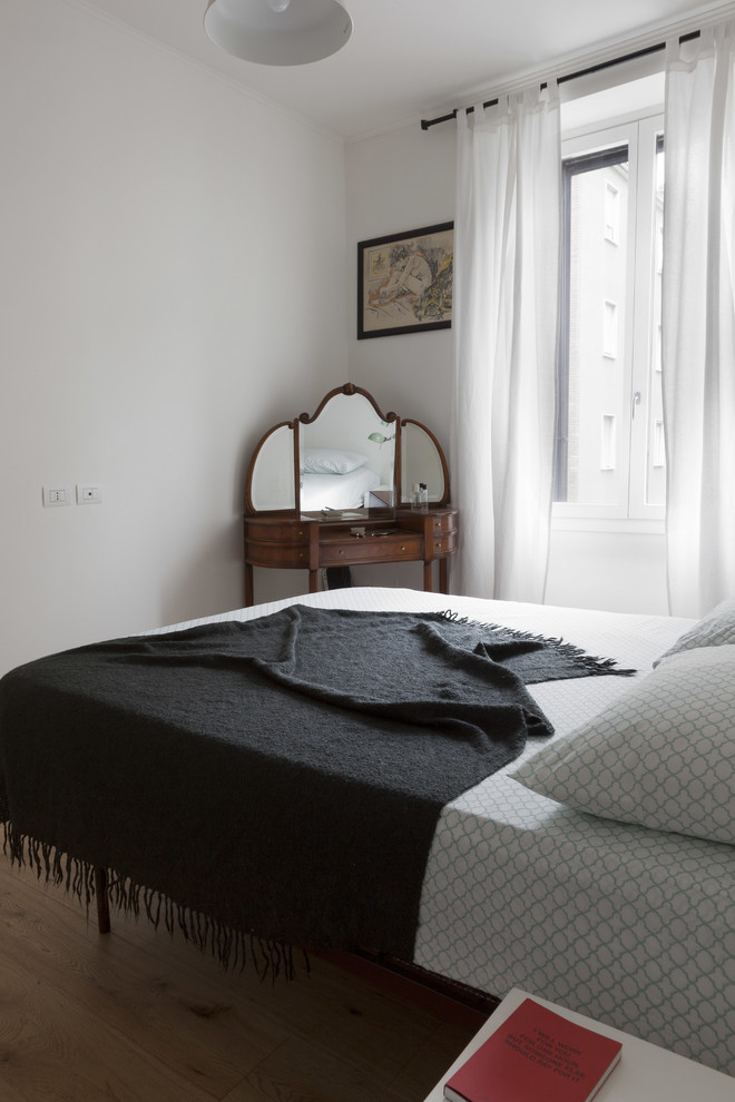 Diseño de dormitorio principal escandinavo de tamaño medio con paredes blancas, suelo de madera clara, chimenea de esquina y suelo marrón