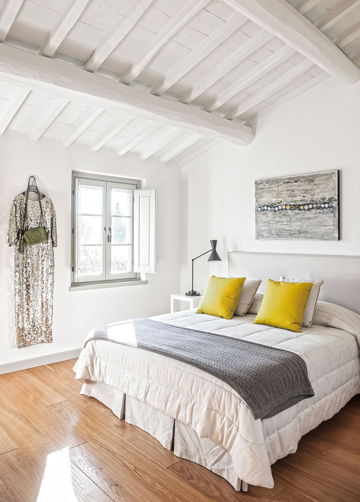 Cette photo montre une chambre méditerranéenne avec un mur blanc et un sol en bois brun.