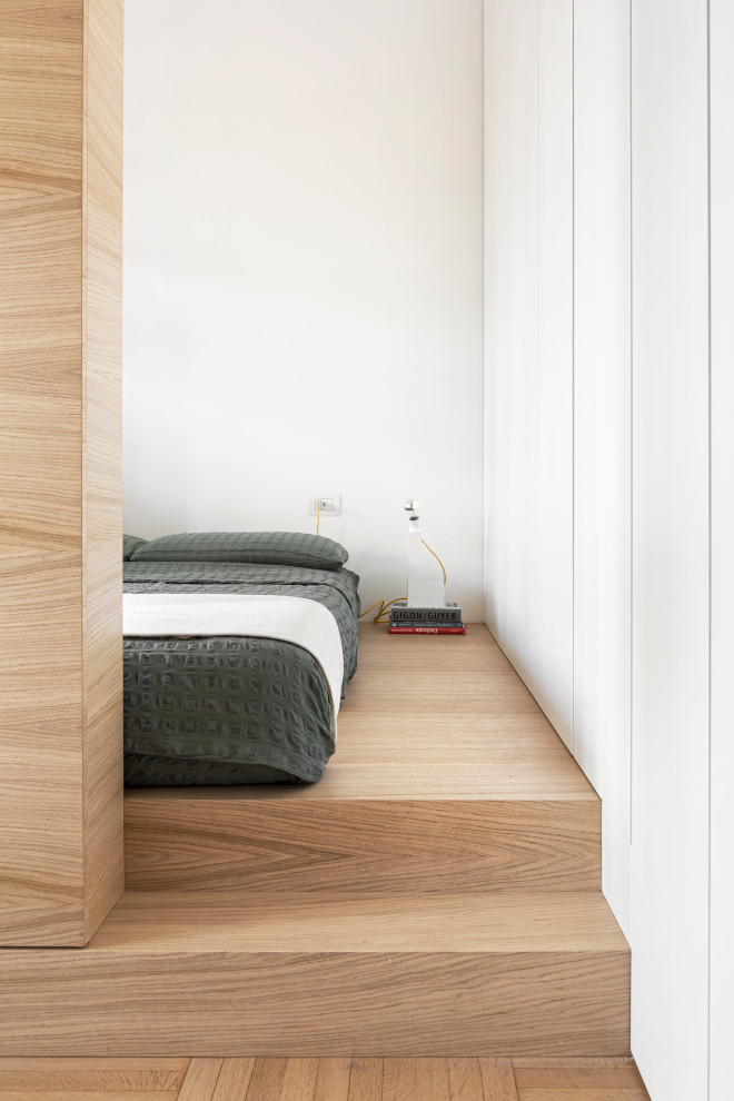 Ispirazione per una piccola camera da letto stile loft contemporanea con pareti bianche e pavimento in legno massello medio