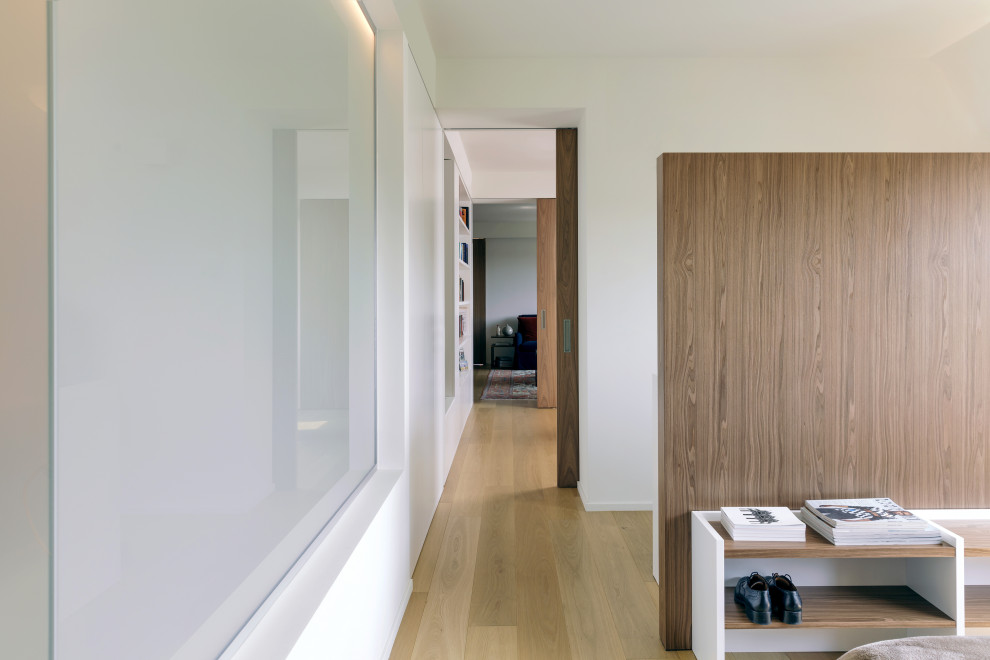 Großes Modernes Hauptschlafzimmer mit weißer Wandfarbe und hellem Holzboden in Mailand