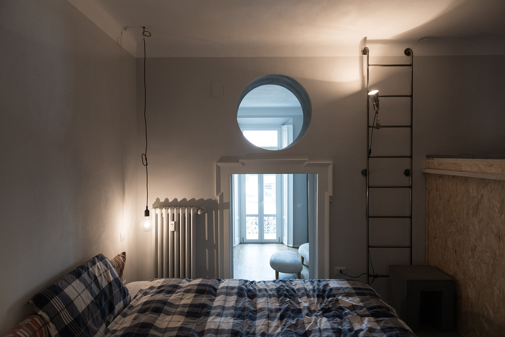 Esempio di una piccola camera da letto stile loft minimal con pareti grigie e pavimento in legno verniciato