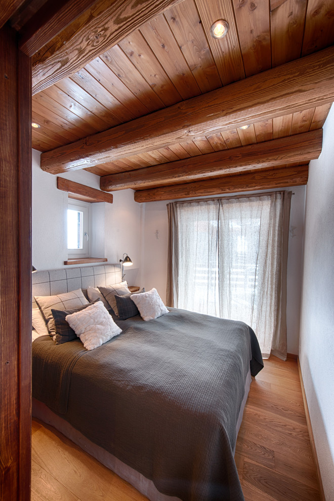 Foto på ett mellanstort rustikt sovrum, med vita väggar och mörkt trägolv