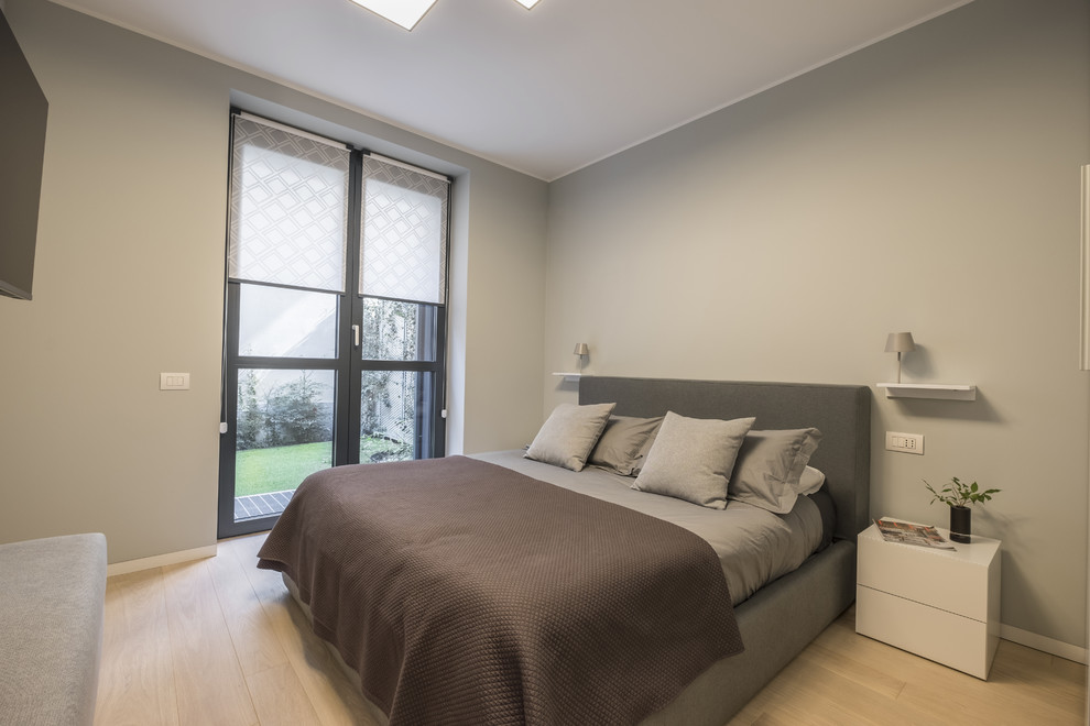 Small modern guest bedroom in Milan with grey walls, light hardwood flooring and yellow floors.