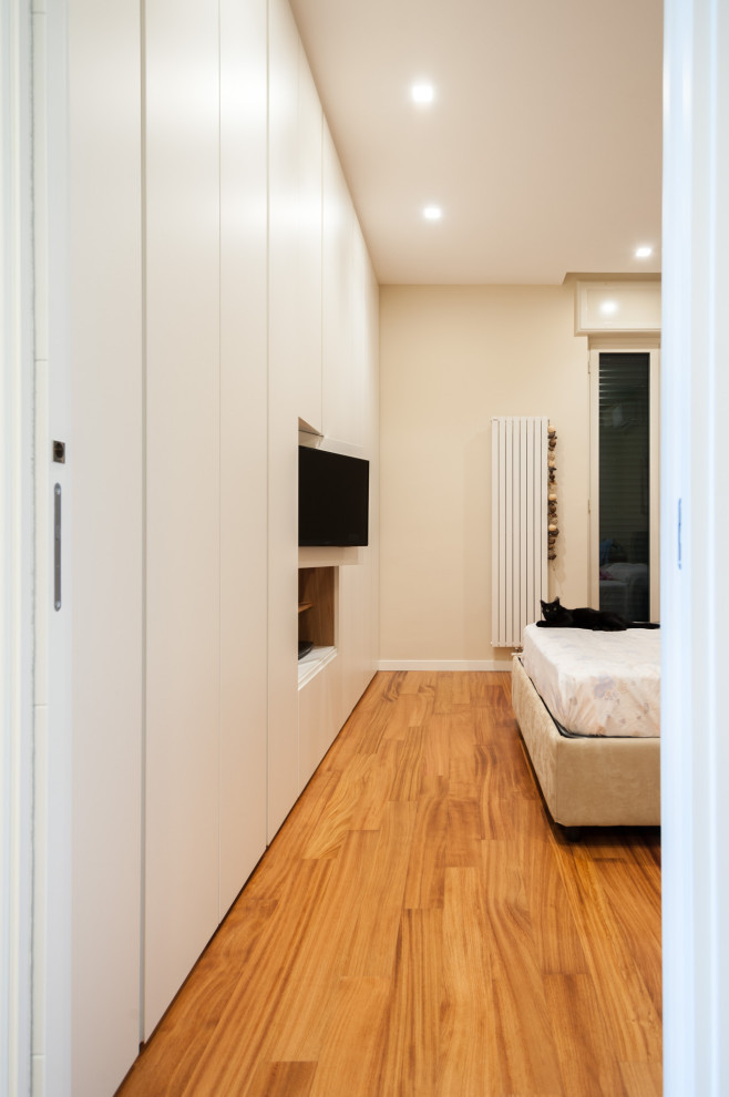 Imagen de dormitorio principal minimalista grande con paredes beige, suelo de madera clara y suelo rojo