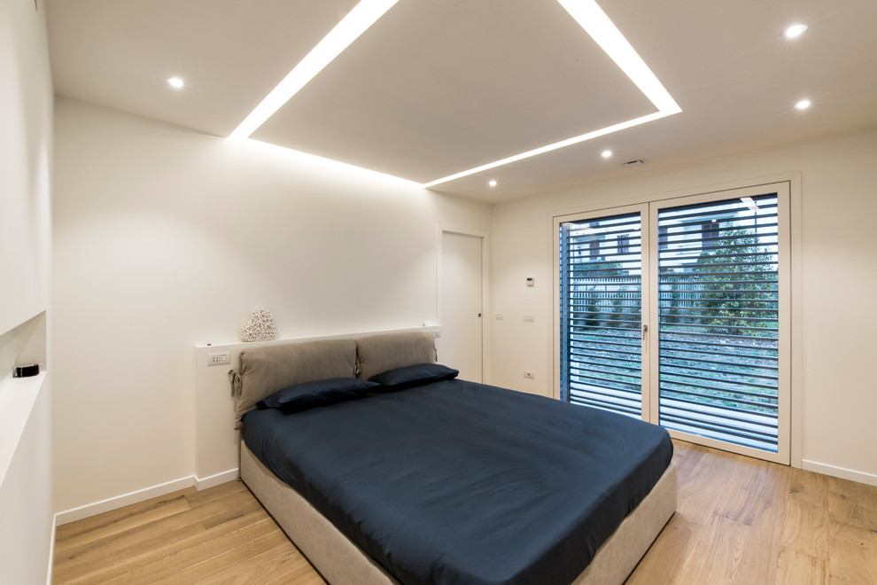 Imagen de dormitorio principal contemporáneo de tamaño medio con paredes blancas y suelo de madera clara