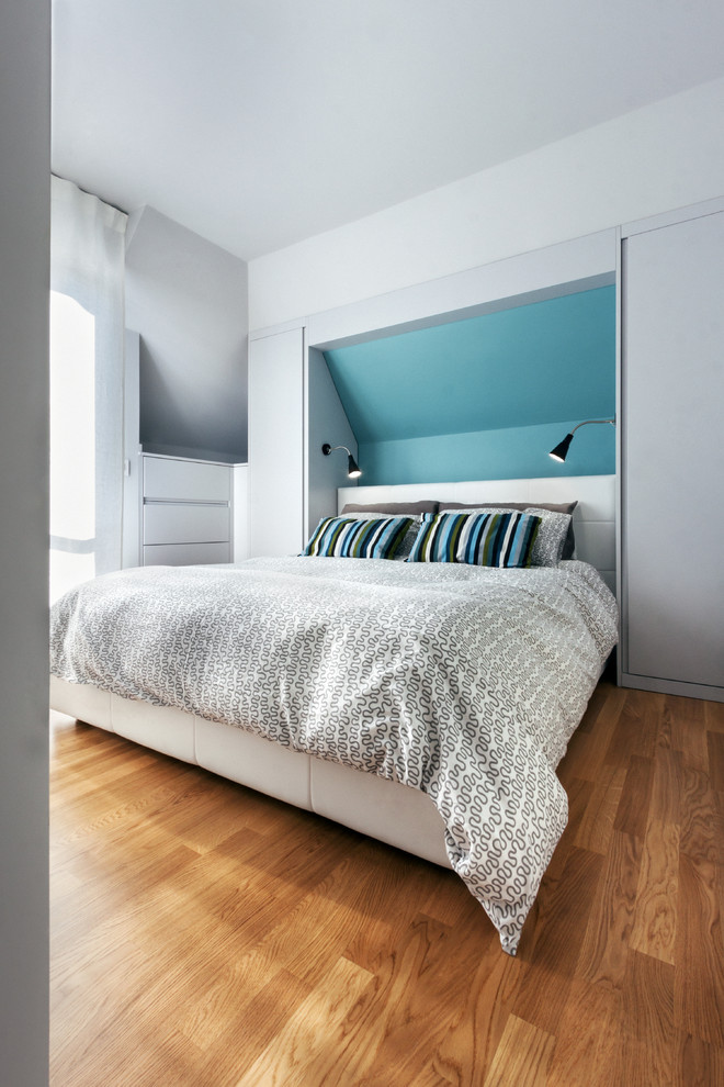 Modelo de dormitorio principal contemporáneo pequeño sin chimenea con paredes blancas, suelo de madera en tonos medios y suelo marrón