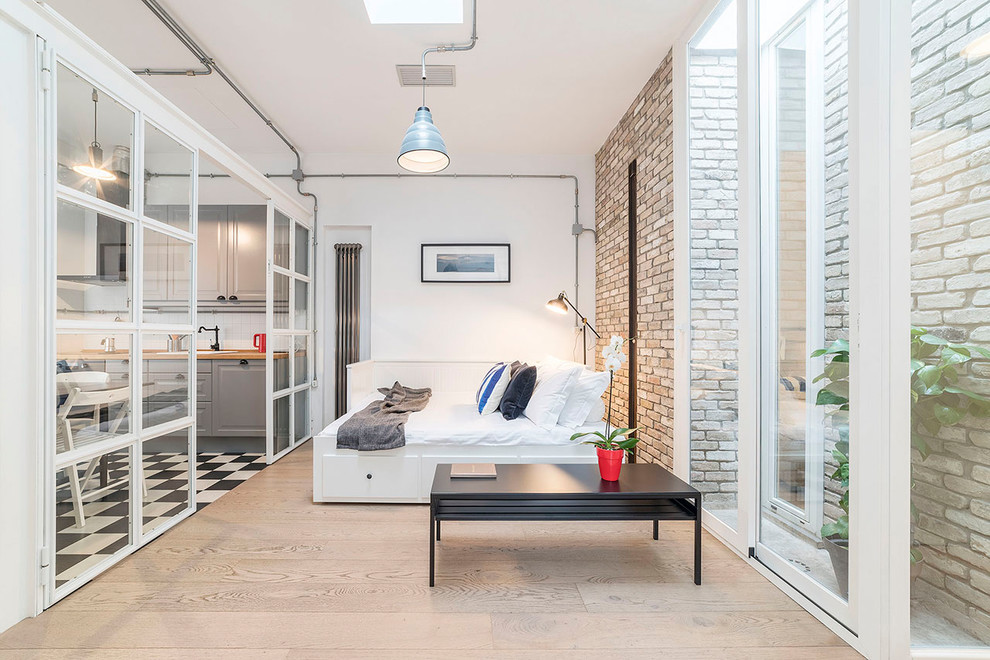 Ejemplo de dormitorio industrial con paredes blancas, suelo de madera clara y suelo beige
