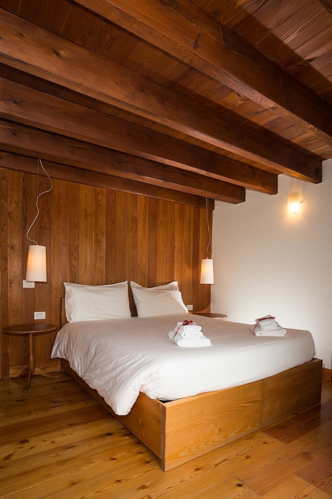 Foto de dormitorio rural de tamaño medio con suelo de madera en tonos medios y paredes blancas
