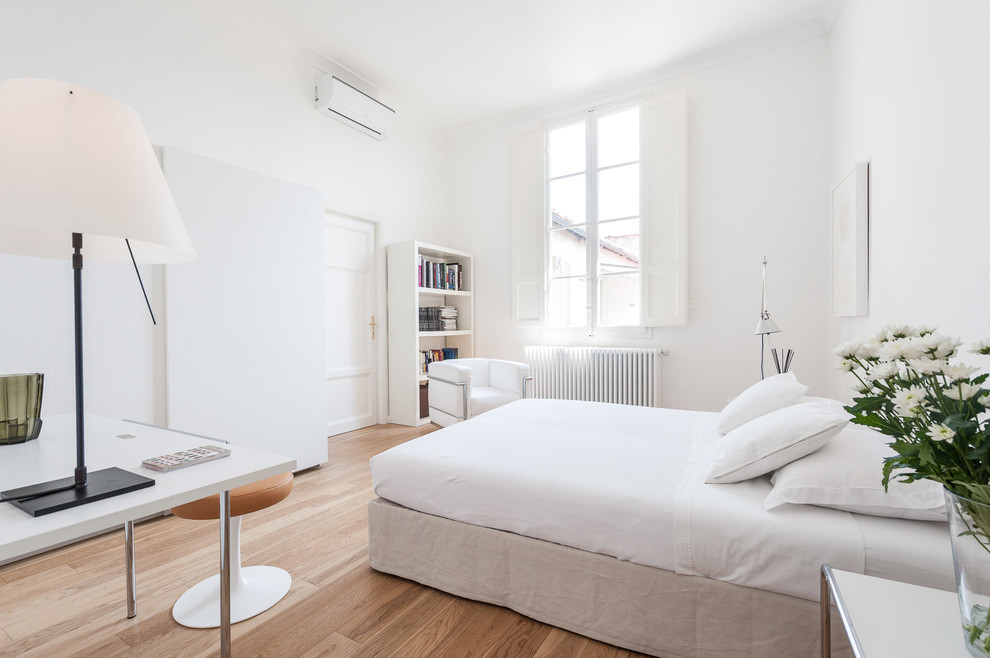 Ispirazione per una camera da letto design con pareti bianche, pavimento in legno massello medio e pavimento marrone