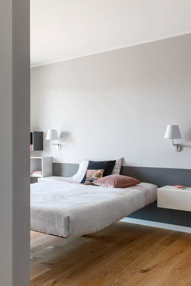 Modelo de dormitorio principal actual de tamaño medio con paredes grises y suelo de madera clara